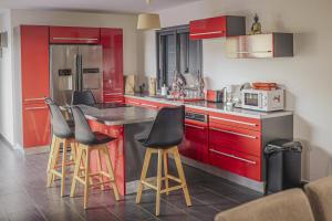 a kitchen with red cabinets and bar stools at Baril Sucré - Piscine- Jardin - By Sister Home in Saint-Philippe