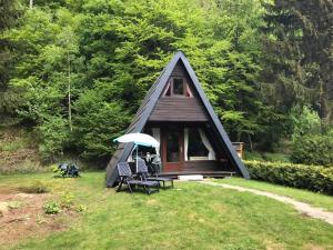 a cabin with a bench and an umbrella in the grass at Ferienhaus Mit Garten, Grill Und Terrasse in Langelsheim
