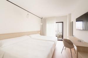 a white bedroom with a large bed and a desk at Hotel RH Arena - Todo Incluido in Gandía