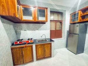 a kitchen with wooden cabinets and a stainless steel refrigerator at Stone House & Apartment 3 in Zanzibar City +26 photos