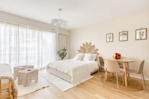 Un dormitorio blanco con una cama y una mesa. en Bohemian Nuance - 15 min from Orly - Calme & Elégance, en Antony
