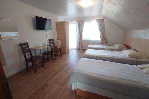 a hotel room with two beds and a table and chairs at Pensiunea San in Arad