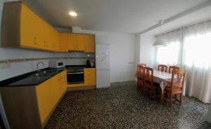 a kitchen with yellow cabinets and a table and chairs at CASA Dúplex Peñíscola in Peniscola