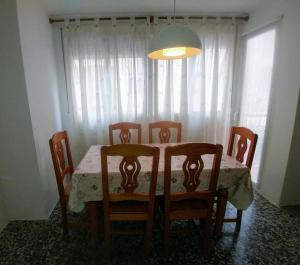 a dining room table with four chairs and a white curtain at CASA Dúplex Peñíscola in Peniscola +9 photos