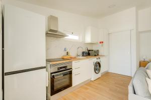 a kitchen with white cabinets and a stove top oven at Charming Aroeira Beach Studio in Aroeira