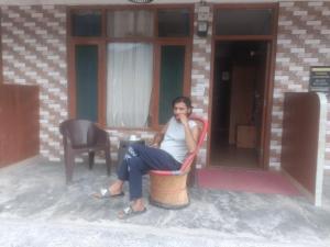 una mujer sentada en una silla hablando por celular en Habitat Cottages, en Bashist