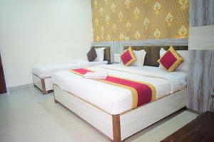 two beds in a hotel room with white sheets at Vinayak shree hotel in Indore