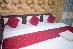 a bed with red and white pillows on it at Vinayak shree hotel in Indore
