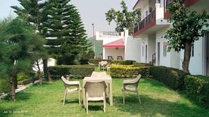 a table and chairs in the grass next to a building at Mohdev Resort in Jhājra