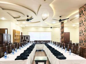 a banquet hall with long tables with black chairs at Hotel One University Sukkur in Sukkur