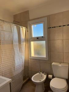 Un baño con inodoro, lavabo y ventana. en ByF apart duplex excepcional en complejo Amaiur DPTO N5 Av Alem Norte, en Federación