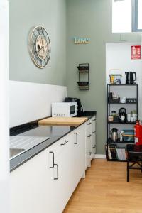 a kitchen with white cabinets and a clock on the wall at Hostel Time Life in Nerja