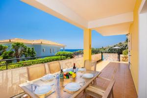a dining table on the balcony of a house at Skala Villa Yellow in Skala Kefalonias