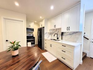 a kitchen with white cabinets and a wooden table at Newly built three bedroom close to Rodeo Drive Hollywood Downtown and Beaches Close to attractions in Los Angeles