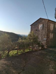 an old stone building with trees and a fence at Casa Rossella - Cinque Terre in Corvara