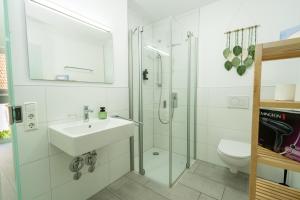 a white bathroom with a sink and a shower at Sali Homes Apartmenthaus Schlossgasse in Neckarsulm +33 photos
