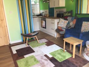 a living room with a blue couch and a kitchen at The Barn Seaside Studio - Sleeps 2 & Hot Tub in South Hayling