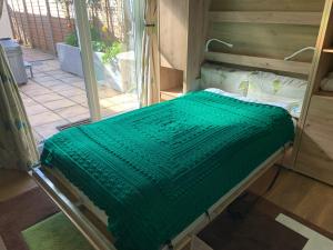 a hospital bed with a green blanket on it at The Barn Seaside Studio - Sleeps 2 & Hot Tub in South Hayling