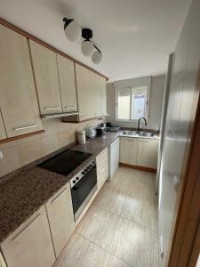 a kitchen with white cabinets and a sink and a stove at Medeea's Spanish Sunny Escape in Vinarós