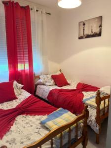 2 letti in una camera con tende rosse di Apartamentos Sardiñeiro a Fisterra (Finisterre) Altre 16 foto