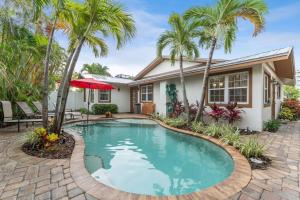 a swimming pool in front of a house with palm trees at Villa La Esperanza-Holmes Beach 201 in Anna Maria Island