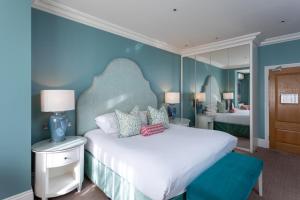 a bedroom with a large white bed with blue walls at Roslin Beach Hotel in Southend-on-Sea