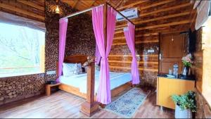 Kota BāghKK Jungle View Resort的一间卧室配有一张带粉红色窗帘的天蓬床