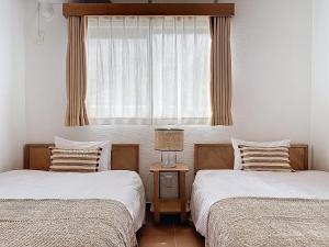 two twin beds in a room with a window at ulu Okinawa Resort in Motobu +30 photos