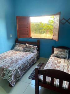 two beds in a room with a window at Recanto Boa Vista in Pirenópolis +3 photos