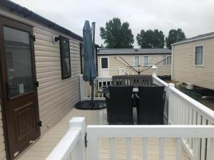 a deck with a table and an umbrella at Stunning 6 Berth Caravan For Hire At Norfolks Seashore Haven Park Ref 22005Ev in Great Yarmouth +10 photos
