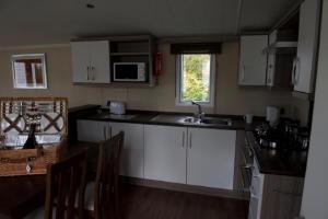 a kitchen with white cabinets and a sink at Stunning 6 Berth Caravan For Hire At Norfolks Seashore Haven Park Ref 22005Ev in Great Yarmouth