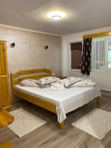 ein Schlafzimmer mit einem großen Bett mit weißen Laken und Kissen in der Unterkunft Pensiunea Cerbul in Lacul Roşu