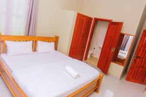 a bedroom with a white bed with a mirror at 4Luxury Hotel in Moshi +6 photos