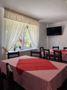 ein Esszimmer mit zwei Tischen und einem Fenster in der Unterkunft Pensiunea Cerbul in Lacul Roşu