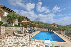 ein Pool mit Stühlen und Sonnenschirmen neben einem Haus in der Unterkunft Liofoto in Skopelos