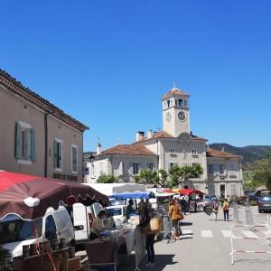 ein Markt in einer Stadt mit einem Glockenturm in der Unterkunft Appartement en cœur de village au pied du château avec 2 balcons in Alba-la-Romaine + 4 Fotos