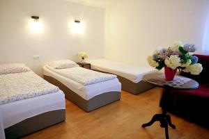a room with three beds and a table with a vase of flowers at Domek pod Zatorem in Ryczów