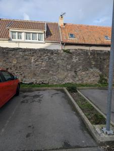 a car parked in a parking lot next to a stone wall at WimSaens in Wimereux
