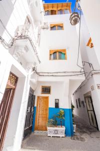 a white building with a wooden door and a plant at Chambre au cœur de la médina avec salle de bain privé in Tangier