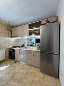 a kitchen with a stainless steel refrigerator and cabinets at Casa Trei Brazi Bratca in Bratca
