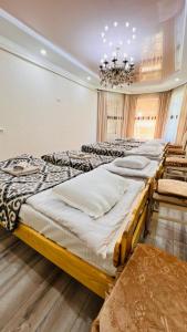 a group of beds in a room with a chandelier at Guest House Ormon in Ak-Muz