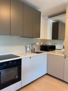 a kitchen with white cabinets and black appliances at Apartmán Grand in Prešov