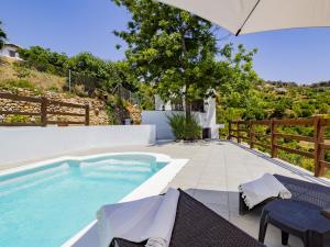 a swimming pool with two chairs and an umbrella at Cubo's Casa Rural Jaramago in Yunquera