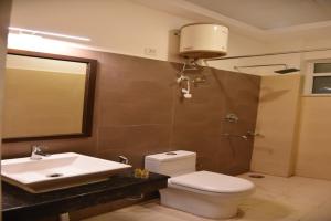 a bathroom with a toilet and a sink and a mirror at RROOMS Hotel Riddhi Grand in Lucknow