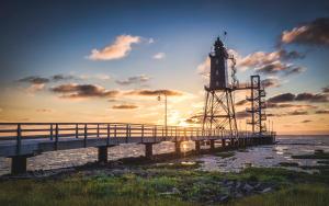 a lighthouse on a pier next to the water at Dorumer Sielhuus 20 mit Sauna und Balkon in Dorum