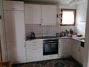 a kitchen with white cabinets and a black oven at Ferienhaus mit Berg-und Seesicht in Filzbach