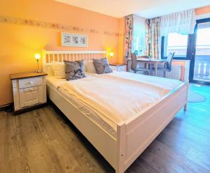 ein großes weißes Bett in einem Zimmer mit einem Tisch in der Unterkunft Haus Sabine - Zimmer 2 in Braunlage