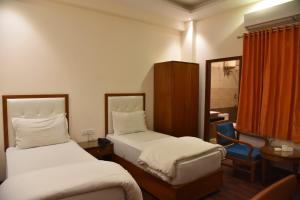 a hotel room with two beds and a mirror at RROOMS Hotel Riddhi Grand in Lucknow