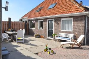 een bakstenen huis met een terras met een tafel en een bank bij Duinhoeve - Farmhouse with fantastic location in Callantsoog