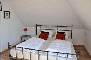 een bed met witte lakens en rode kussens bij Duinhoeve - Farmhouse with fantastic location in Callantsoog